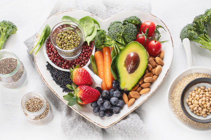 Heart shaped plate full of fruit, veg and nuts which are suitable for a vegan diet