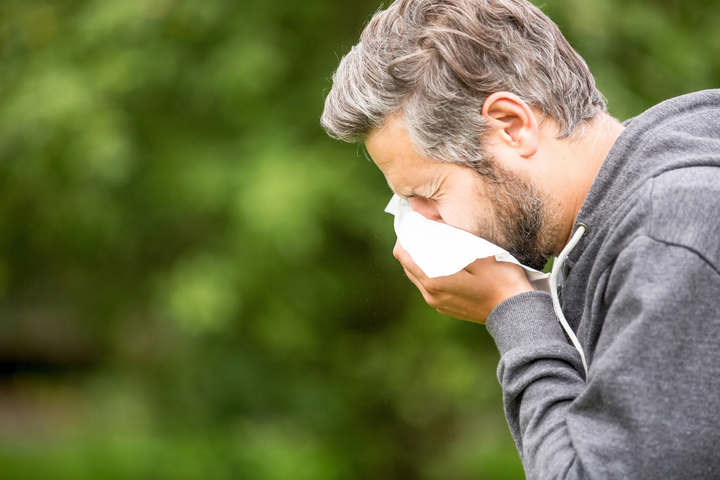 Man Sneezing into a tissue